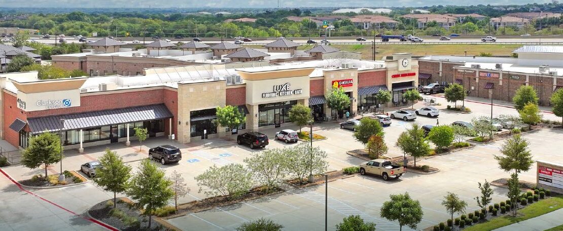 Independence Plaza retail shopping center with red brick storefronts and highway access in Frisco, Texas